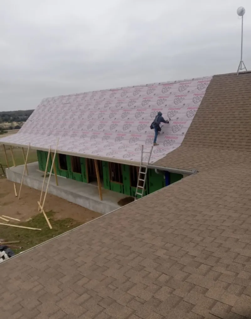 Worker preparing underlayment for a metal roof installation in Winchester